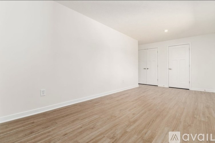 A room with wooden flooring and two white doors.