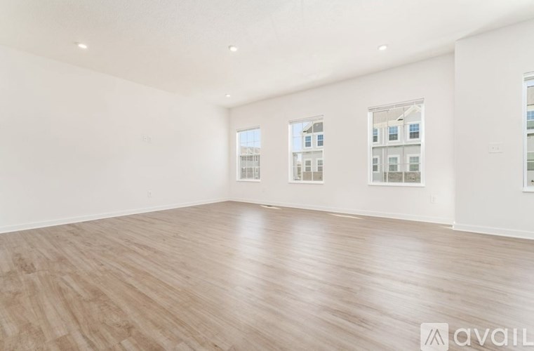 A spacious room with wooden flooring and windows.
