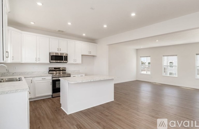 A modern kitchen with white cabinets and a wooden floor.