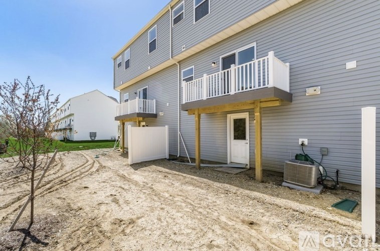 A two-story house with a balcony and a tree in front.