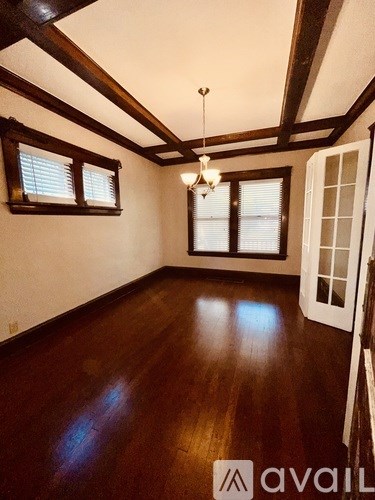A room with wooden floors and a chandelier hanging from the ceiling.