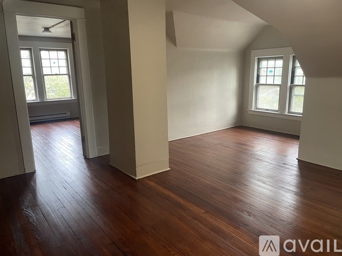 A room with wooden floors and two windows.