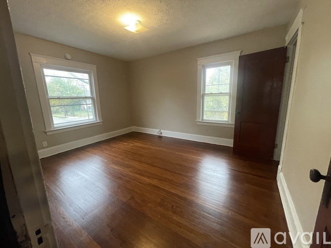 A room with wooden floors and two windows.