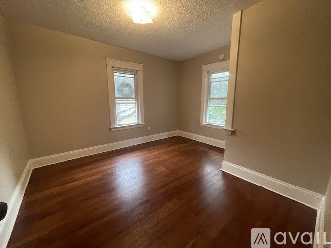 A room with wooden floors and two windows.
