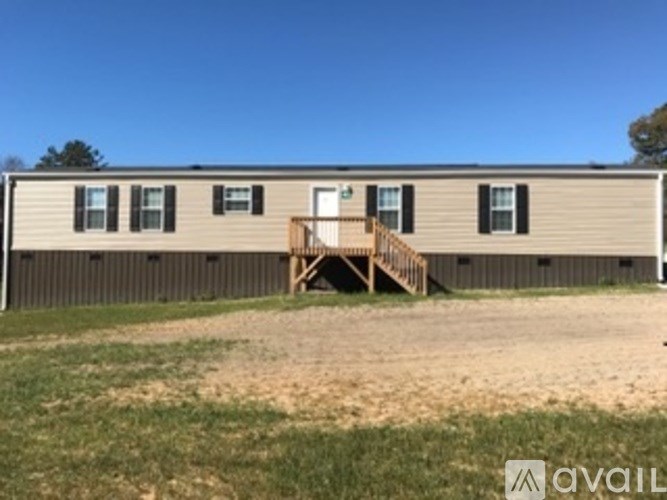 A mobile home with a porch and a brown fence.