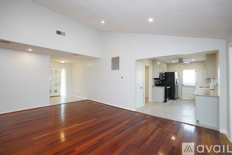 A spacious room with wooden floors and white walls.