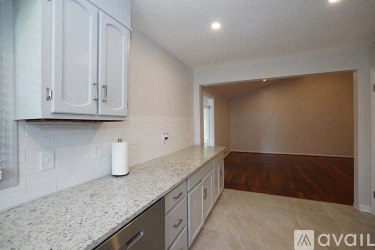 A kitchen with white cabinets and a marble countertop.