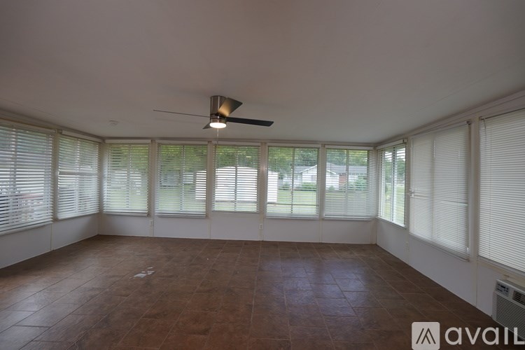 A room with a brown floor and a ceiling fan.