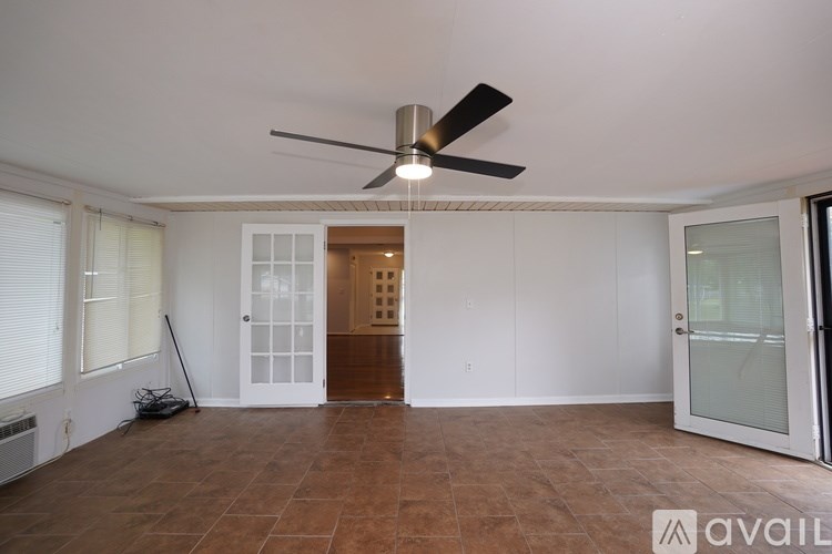 A room with a ceiling fan and brown tile flooring.