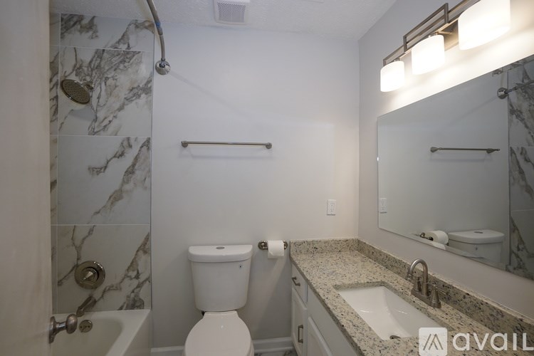 A bathroom with a marble tile shower and toilet area.