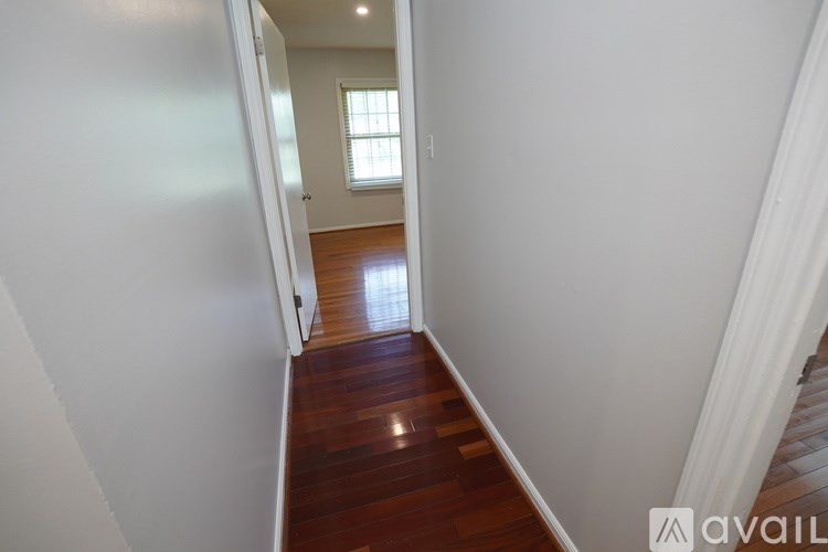 A hallway with a wooden floor and white walls.
