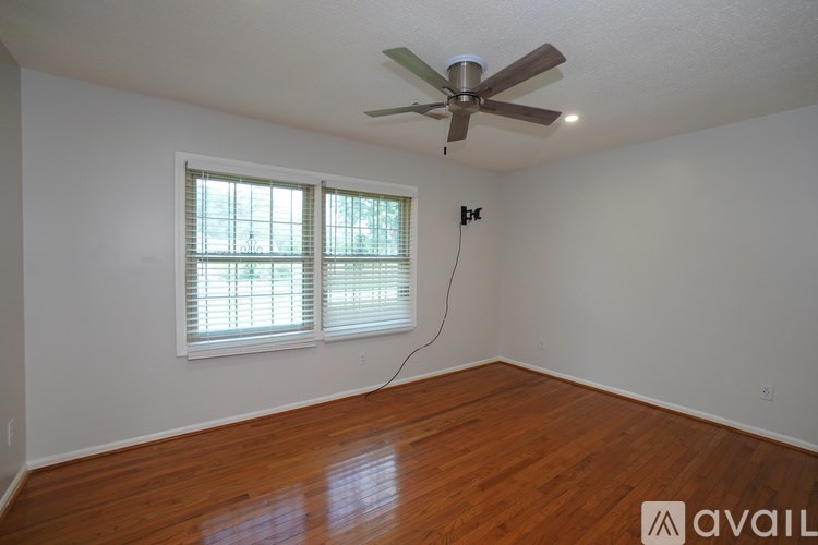 A room with a ceiling fan and a window with blinds.