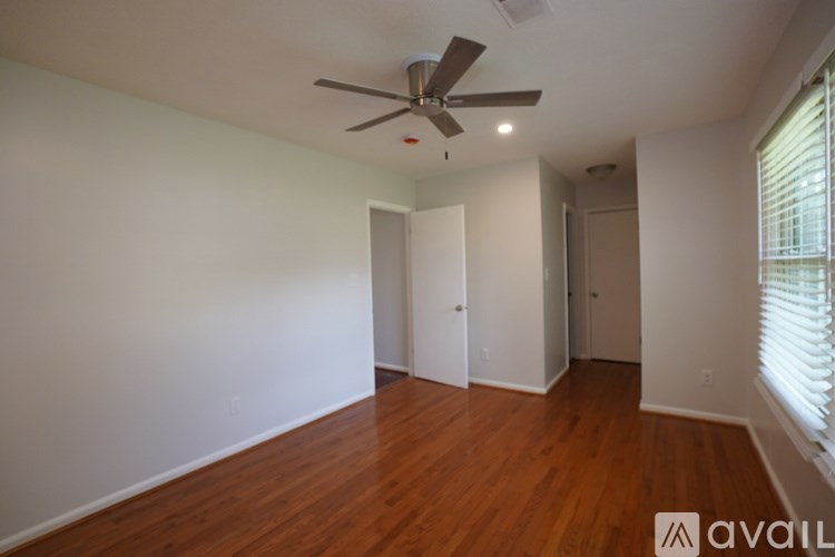 A room with a ceiling fan and wooden floors.