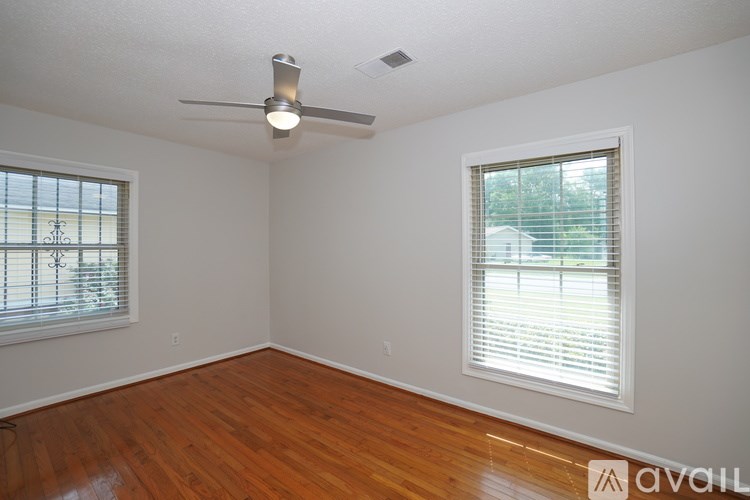 A room with a ceiling fan and two windows.