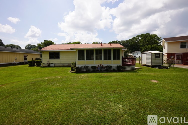 A house with a red roof is surrounded by a fence and other houses.