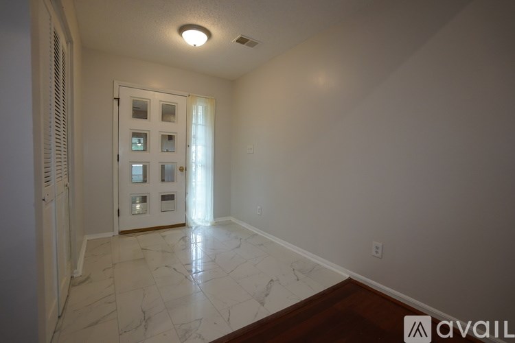 A room with a white door and a marble floor.