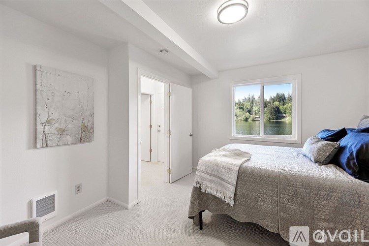 A bedroom with a large bed and a window overlooking a green landscape.