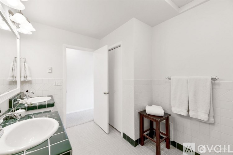 A bathroom with a white sink and green tiles.