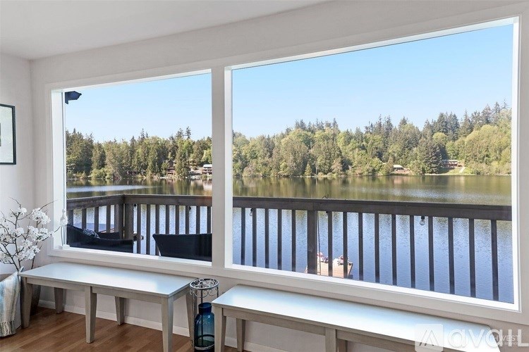 A living room with a large window overlooking a lake and forest.