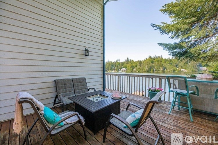 A wooden deck with a table and chairs overlooking a forest.