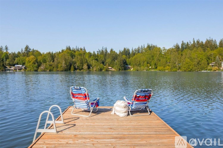 Two chairs are on a dock by the water.