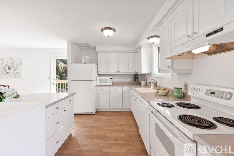 A white kitchen with wooden floors and white appliances.