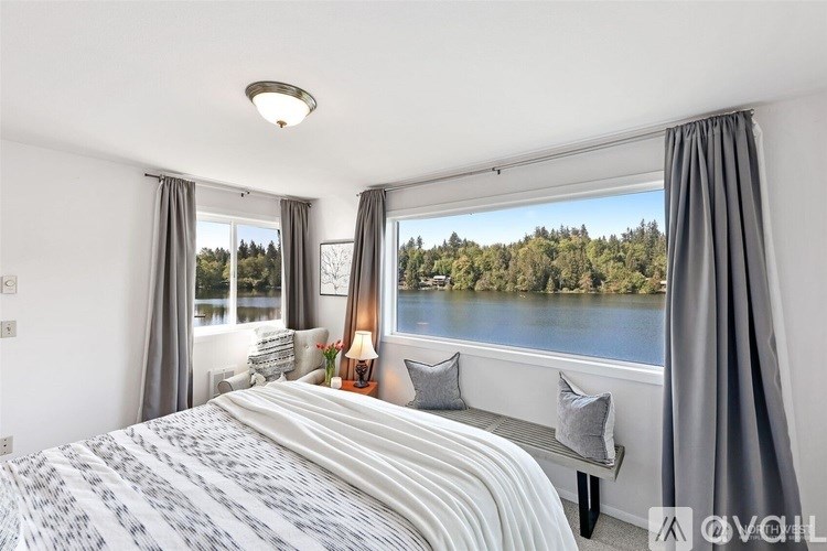 A bedroom with a large bed and a view of a lake.