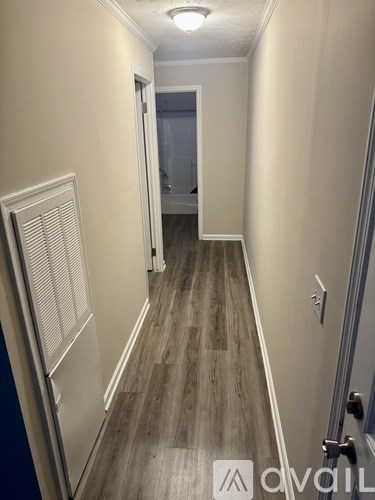 A hallway with wood flooring and white walls.