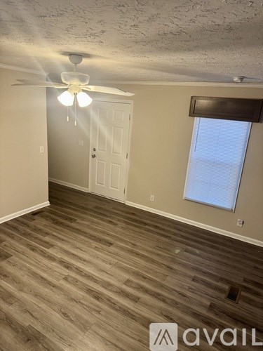 A room with a ceiling fan and wooden flooring.