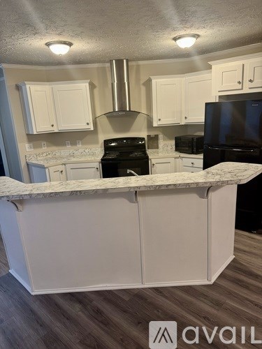 A kitchen with white cabinets and a marble countertop.