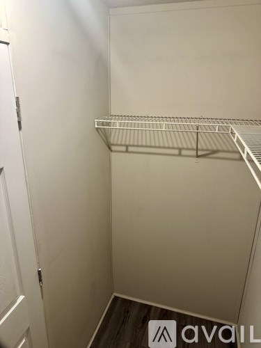 A small, empty walk-in closet with a metal rack and a white door.