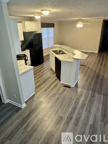 A kitchen with a black fridge and white cabinets.