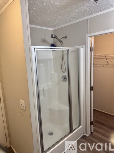 A glass shower door in a bathroom with a hanger on the wall.