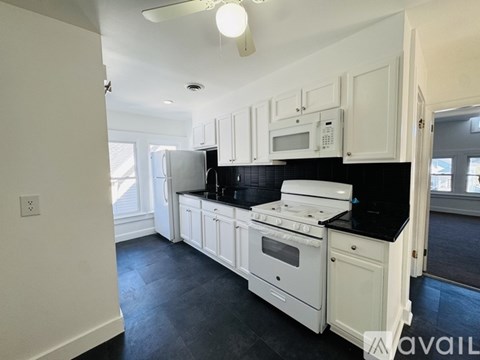 A kitchen with white cabinets and black countertops.