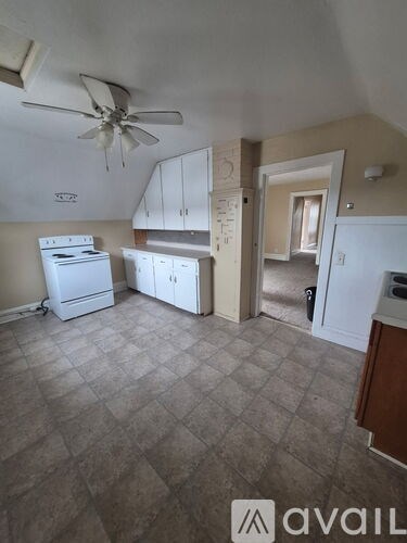 A kitchen with a white fridge and a fan on the ceiling.