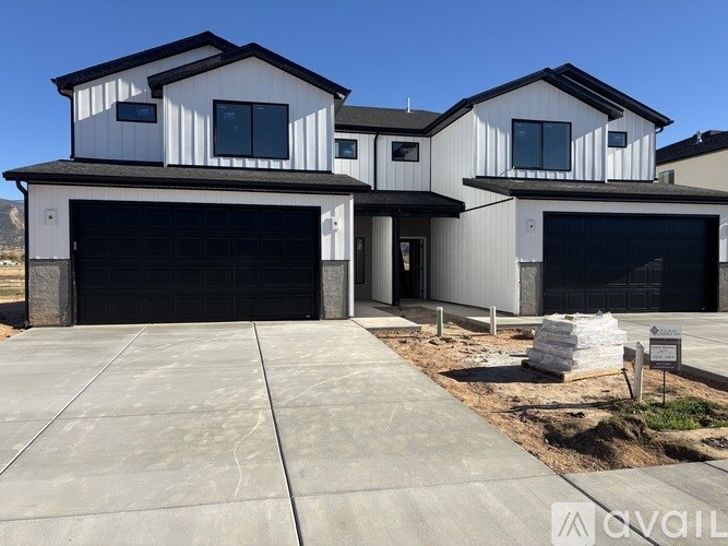 A modern two-story house with a garage door and a driveway.