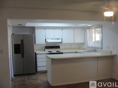 A kitchen with white cabinets and a refrigerator.