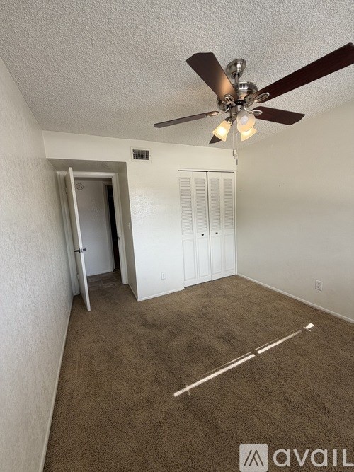 A room with a ceiling fan and a carpeted floor.