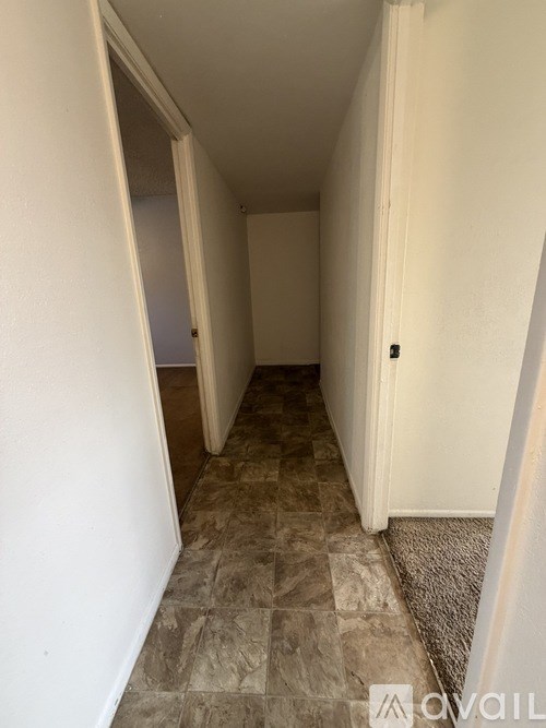 A hallway with tiled flooring and white walls.