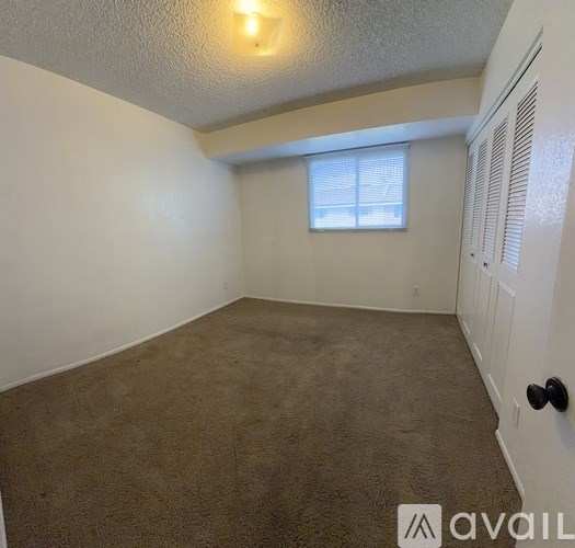 A room with a carpeted floor and a window with blinds.