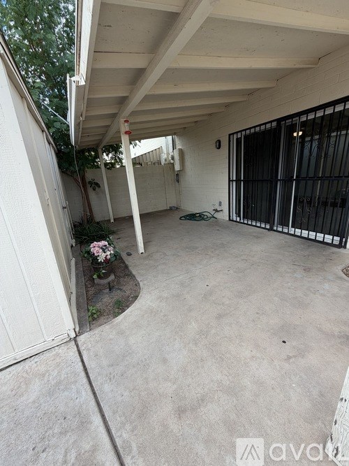 A patio area with a white wall and a black gate.