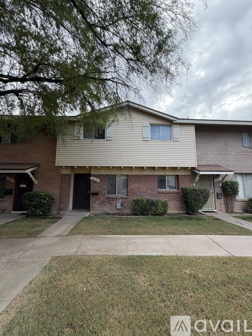 A house with a grey roof and a tree in front.
