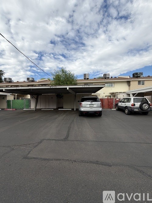 A parking lot with a few cars and a building in the background.