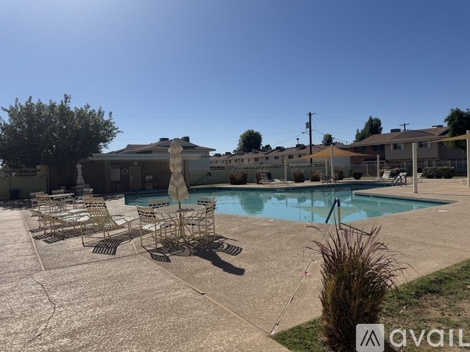 A pool with chairs around it and a house in the background.