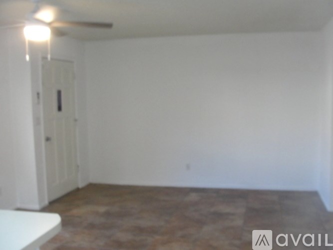 A room with a white door and a ceiling fan.