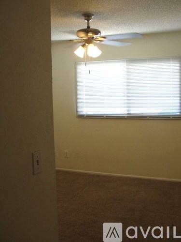 A room with a ceiling fan and a window with blinds.