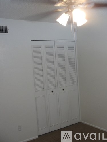 A room with a ceiling fan and a cabinet with two doors.