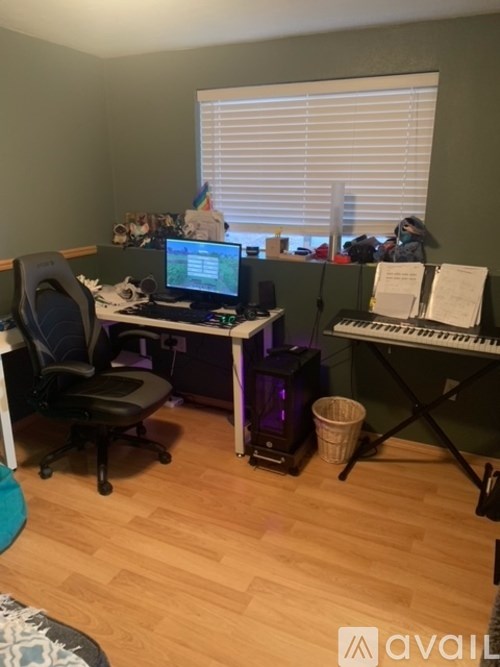 A room with a desk, chair, keyboard, and a computer monitor.