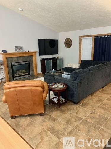 A living room with a grey couch, a brown chair, and a fireplace.