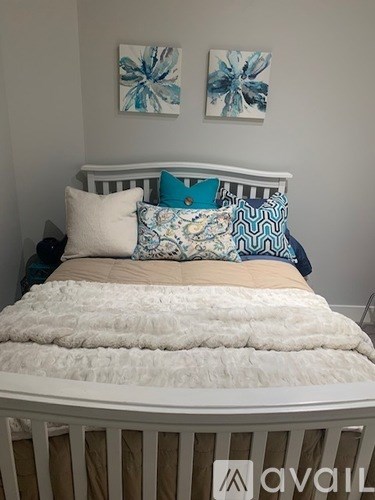 A bed with a white comforter and blue and white pillows.